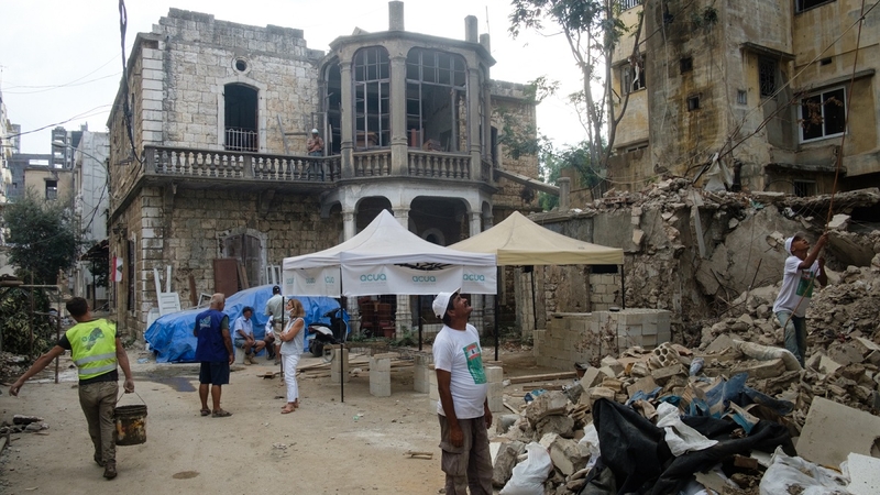 An old building stands before the ruins, aid and construction workers nearby. Karantina, Beirut. September 23, 2020. (Rita Kabalan/The Public Source)