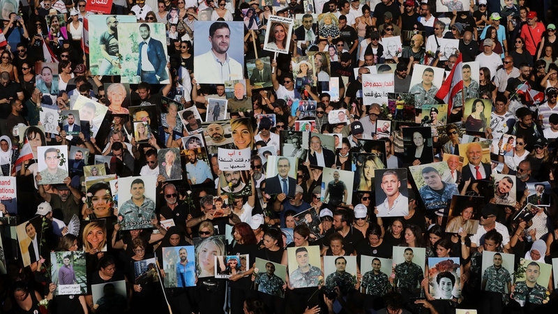 A large crowd of thousands of people walking together, carrying posters and photos.