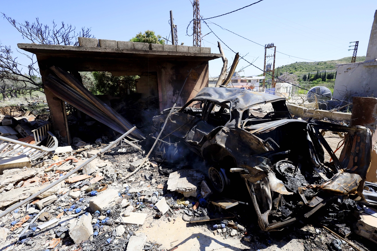 A destroyed car amid the wreckage of a destroyed home