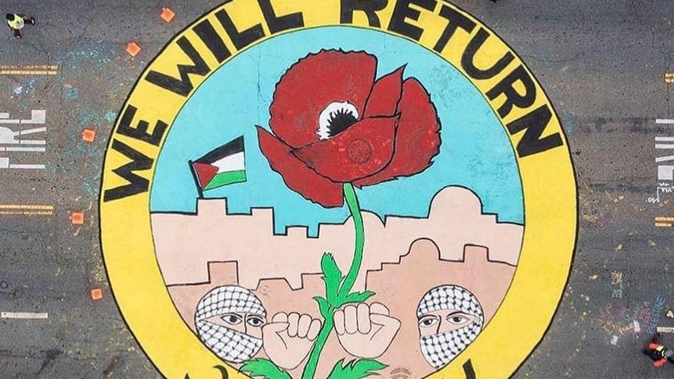 Street art of a red poppy at the center of a circle that also contains two people with kuffiyas wrapped around their heads, their fists in the air, and the Palestinian flag in the background. The graffiti reads: "WE WILL RETURN".