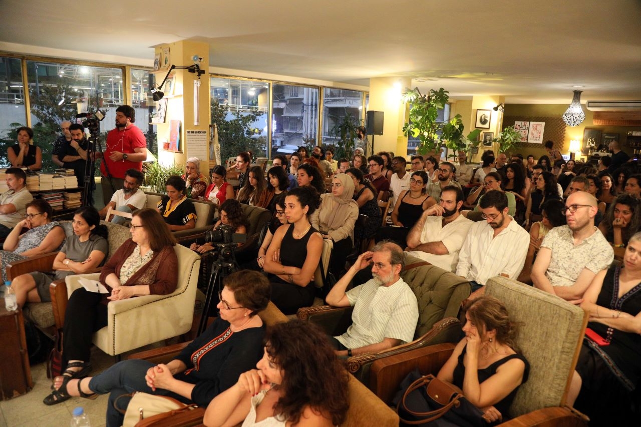 A small number of people sit next to each other at Barzakh Bookshop, Hamra to watch Arundhati Roy speak. 