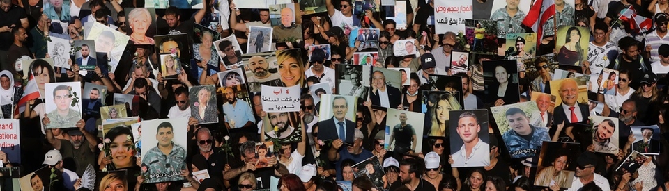 A large crowd of thousands of people walking together, carrying posters and photos.