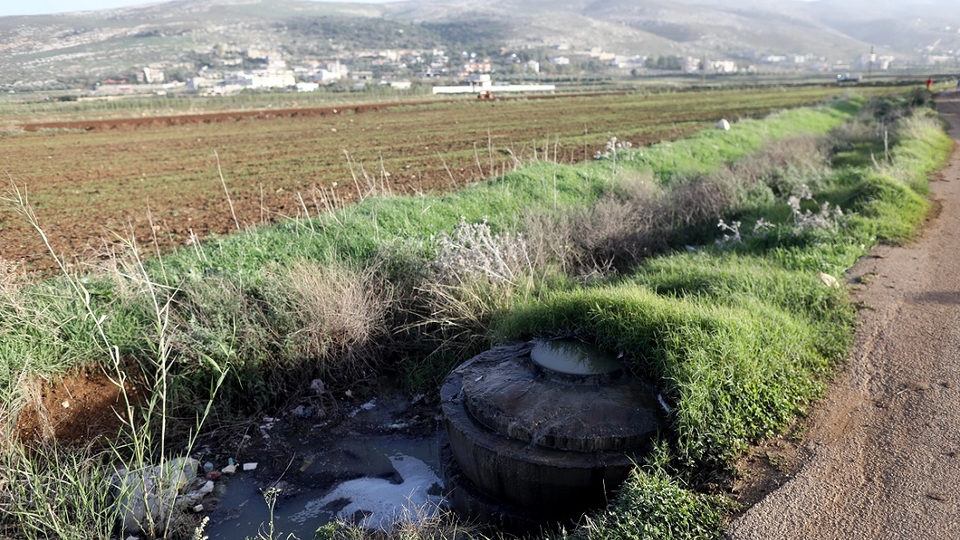 Open manhole pouring sewage water into a canal bordering an agricultural land in Akkar.